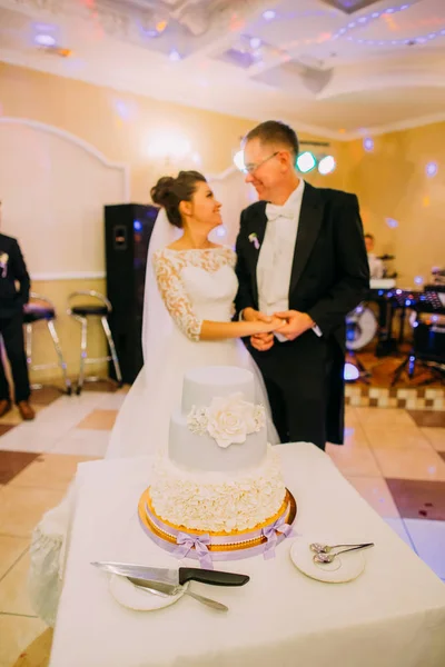 La torta bianca di marzapane con fiori sullo sfondo degli sposi felici . — Foto Stock