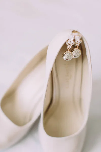 Серебряные серьги на бежевых свадебных каблуках . — стоковое фото