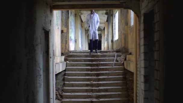 Lo psicoterapeuta afro-americano sta camminando lungo i corridoi rovinati dell'ospedale abbandonato . — Video Stock