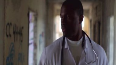 Ciddi sakin Afrika psikoterapist terk edilmiş akıl hastanesi eski yıkık koridorlarda yürüyor.