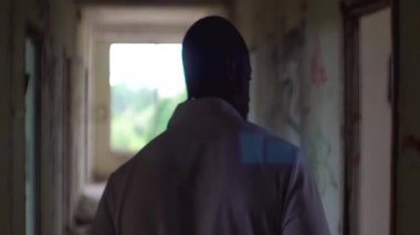 Terk edilmiş Psikiyatri Hastanesi harap corridord yürüyüş bilinmeyen Afrika Doktor arkadan görünüş.