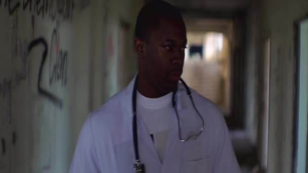 一个自信的非洲医生的肖像沿着被毁的精神病院被毁坏的走廊行走. — 图库视频影像