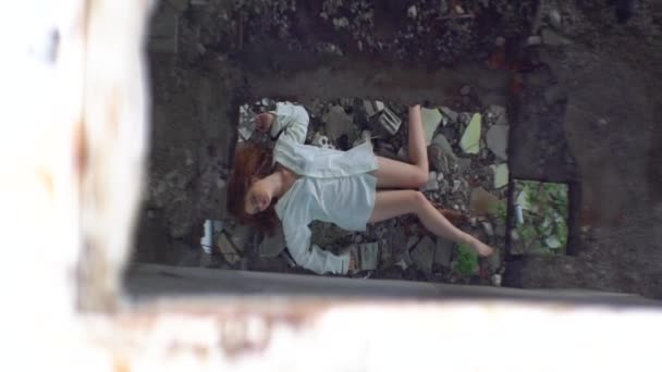 Top view at the sick woman patient in white shirt lying on the ruins of the abandoned mental hospital. — Stock Video