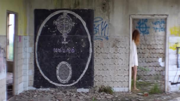 Verlaten psychiatrisch ziekenhuis. Beschadigde muren met graffiti. Onbekende gek rood hoofd vrouw passeren langs de kamer. — Stockvideo