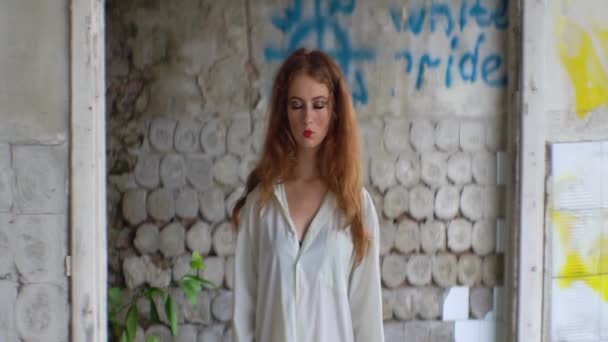 Mysterious red head woman with red lipstick and closed eyes standing over the destroyed wall of the abandoned mental hospital. — Stock Video