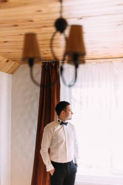 Pencereden bakarken elleri ceplerinde tutmak damat varoluş görünümünü.