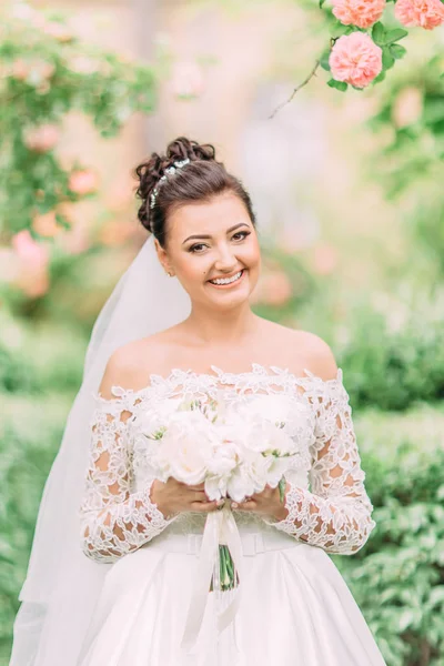 Close-up retrato ao ar livre da noiva alegre com o buquê de casamento . — Fotografia de Stock