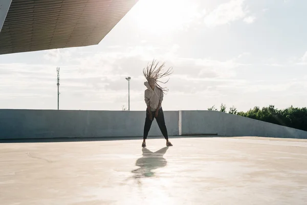 Vista completa de la joven mujer deportiva africana divirtiéndose. Ella está agitando su cabeza en las bengalas del sol . — Foto de Stock