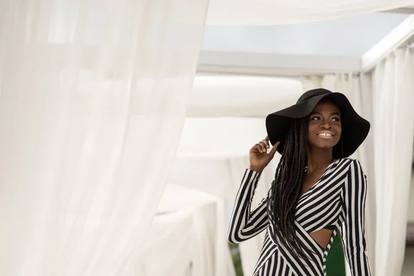 Glücklich afroamerikanisches Mädchen lächelt und posiert für die Kamera auf dem Hintergrund des weißen Stoffes. — Stockfoto