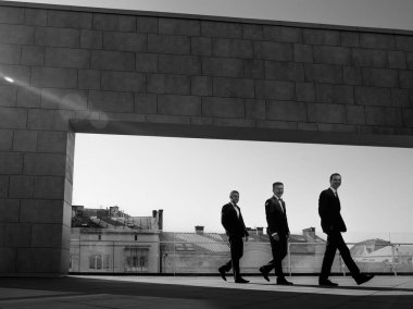 Üç emin gülümseyen iş adamı gökdelenin çatı poz takım elbiseli. Siyah ve beyaz soyut fotoğraf