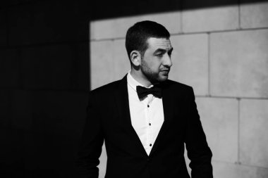 Yakışıklı emin iş kare dokulu duvar poz takım elbiseli adamı sakallı. Siyah ve beyaz soyut fotoğraf