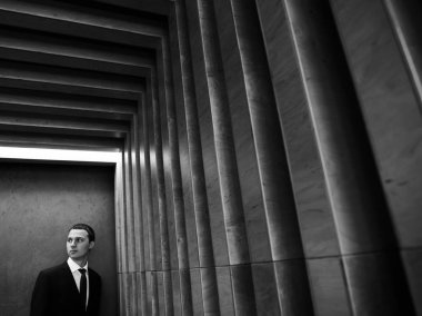 Yakışıklı emin işadamı çizgili dokulu duvar poz takım elbiseli sakallı. Siyah ve beyaz soyut fotoğraf