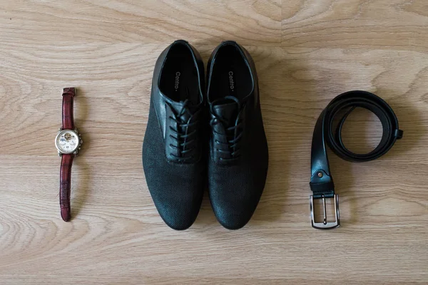 Man wedding accessories. Shoes, watch and black belt on the white wooden background