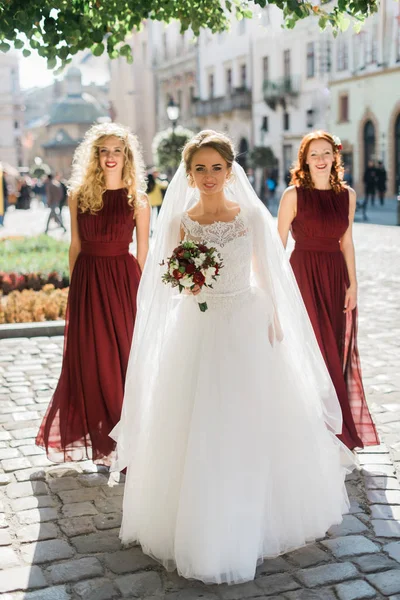 Молодая чувственная невеста с сексуальными подружками невесты позирует на площади старого европейского города — стоковое фото