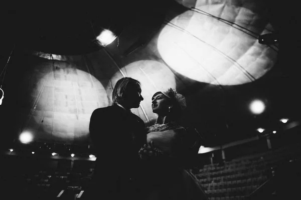 Pareja casada bailando en un escenario retroiluminado. Momento tierno del primer baile. Imagen en blanco y negro. Lujoso estilo de vida —  Fotos de Stock