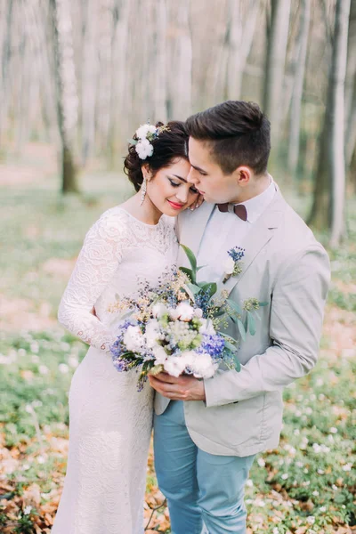 Прекрасная свадебная пара с свадебным букетом весенних цветов в руках в зеленом парке — стоковое фото