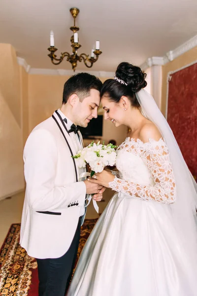 El retrato de medio cuerpo de los recién casados que celebran el ramo de bodas mientras están de pie cabeza a cabeza . — Foto de Stock