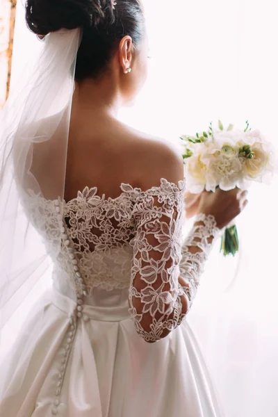 Bela noiva está segurando o buquê de casamento de rosas brancas. A visão de close-up traseira . — Fotografia de Stock