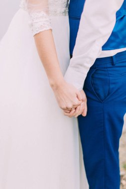 The holding hands of the newlywed couple. clipart