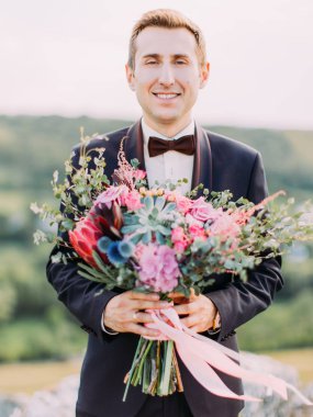 Dikey yakın çekim portre büyük renkli düğün buket tutan gülümseyen damadın.