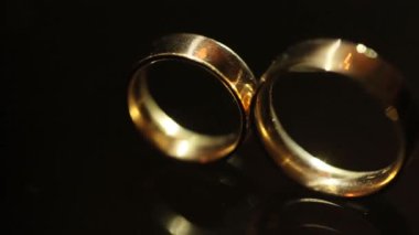 Yakın çekim görünümü koyu arka plan üzerinde yalan altın alyans. Işık demeti Yüzüklerin aydınlatıcı.