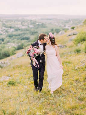 Yeni evliler yürürken öpüşme. Tam uzunlukta görünümü.