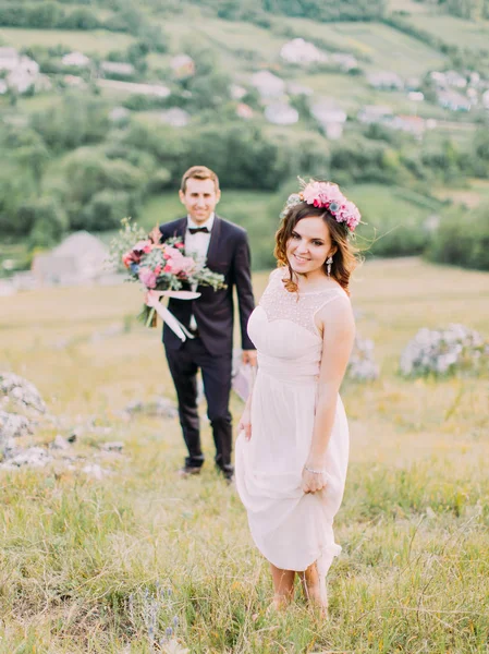 Крупним планом вигляд нареченої стоїть перед розмитим нареченим з весільним букетом . — стокове фото
