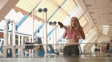Çekici pozitif sarışın sporcumuz masa tenisi veya masa tenisi spor salonunda oynuyor. 4 k görüntüleri.