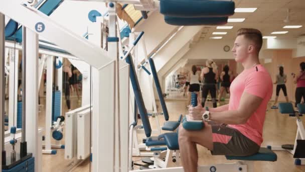 Svalnatý muž sportovec pracuje na strojem nohou lokny ve fitness centru. 4 k video. — Stock video