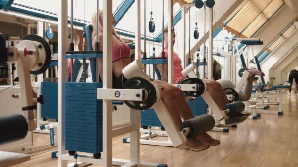 Concepto de estilo de vida saludable. Una joven pareja atlética está haciendo ejercicio en el gimnasio. El yare entrena en los entrenadores de rizos de piernas. Imágenes de 4k . — Vídeos de Stock