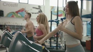Sağlıklı yaşam tarzı kavramı. Üç sportif arkadaş waming kadar treadmill içinde modern bir spor salonu vardır. 4k.