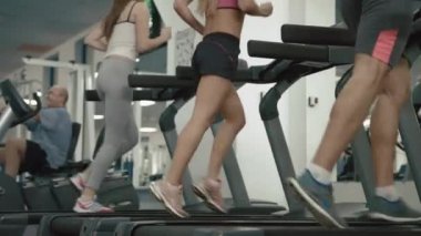 Setler bilinmeyen atletik insanlar koşu bandı üzerinde çalışan tarafından ısınma. 4 k görüntüleri. Yüzü yok. Spor salonu konumu.