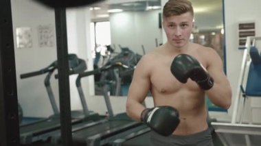 Çıplak gövde kum torbasına modern bir spor salonu, delme ile yakışıklı kaslı boksör. 4k.
