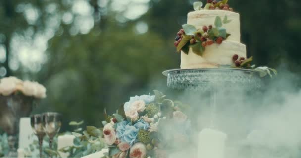 Romantikus időpont összetétele ködös fa. Ízletes két rétegű torta bogyók, csokor virág és gyertya van díszíti tábla. 4k. — Stock videók