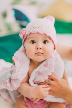 Yakın çekim portre büyük gri gözleri ve örme pembe şapka ile küçük bebek havlu kaplı.