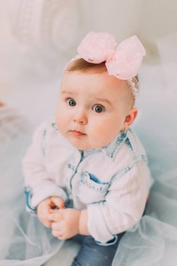 Kafasına fiyonklu bebek güzel tül kaplıdır ve yere oturma. Yakın çekim portre yukarıda