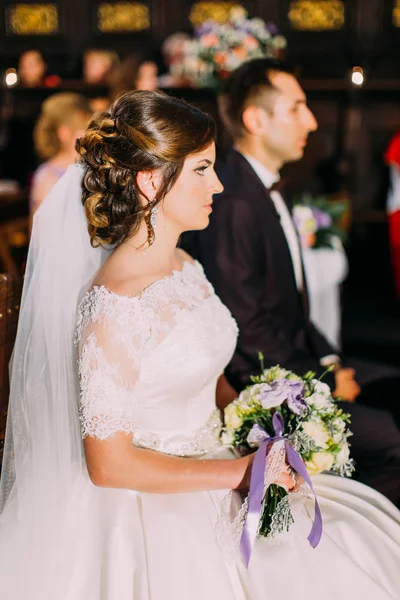 Cerimonia nuziale. Vista laterale degli sposi novelli. Sposa tiene il bouquet di nozze . — Foto Stock