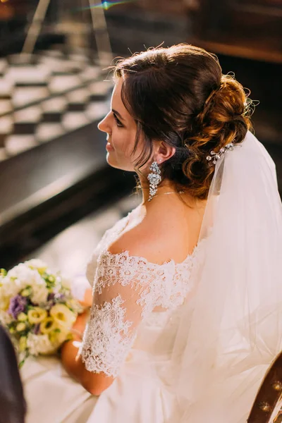 La vista posterior hacia arriba de la hermosa novia sentada en la silla durante la ceremonia de boda en la iglesia . —  Fotos de Stock