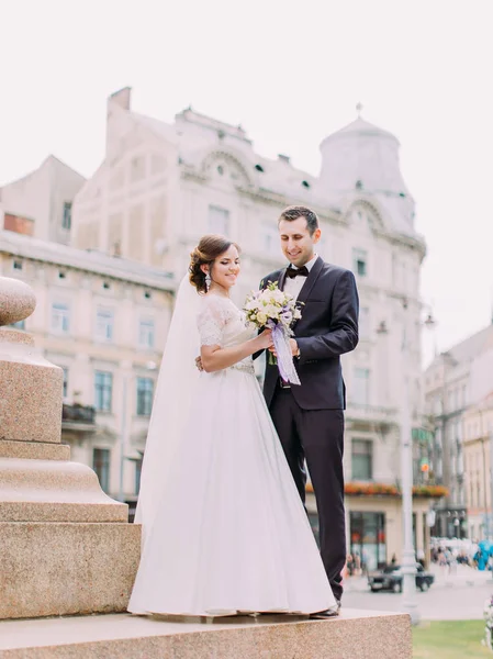 Felices recién casados sosteniendo el ramo de bodas. Foto de larga duración al aire libre . —  Fotos de Stock