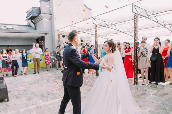 Alegre recién casados están bailando su primer baile bajo la lluvia de confeti . — Foto de Stock