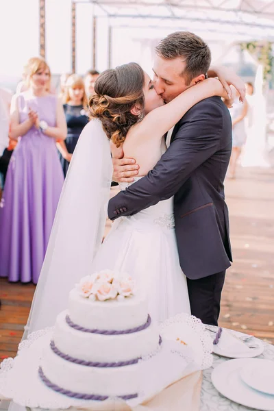 Вертикальне фото поцілунків молодих за весільним тортом . — стокове фото