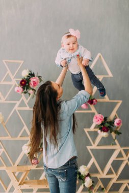 Kafasındaki pembe fiyonklu gülümseyen kızı yetiştirme anne arkadan görünüm.