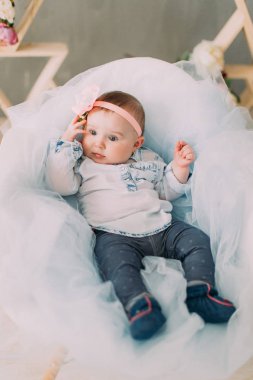 Kafasına çiçekli küçük bebek sol tarafında seyir ve tül üzerinde yalan.