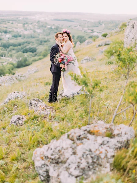 Romantisk utsikt över de krama nygifta stående på klipporna. — Stockfoto