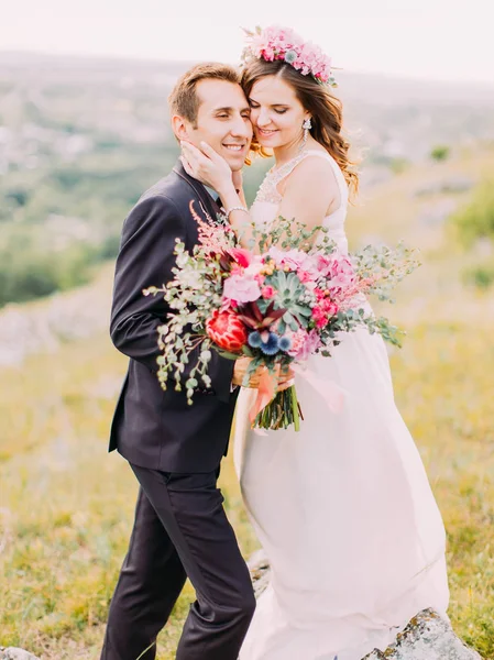 Retrato sensível do abraço sorridente recém-casados segurando o enorme buquê de casamento . — Fotografia de Stock