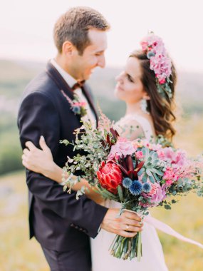 Büyük düğün buket egzotik çiçek gülümseyen yeni evliler, arka plan bulanık.