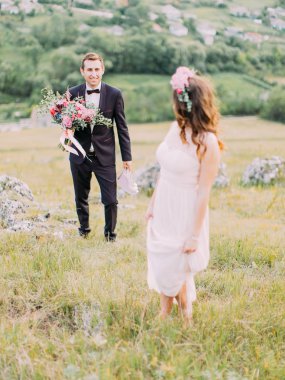 Damat düğün buket ile gelini çayırda için yürüyor.