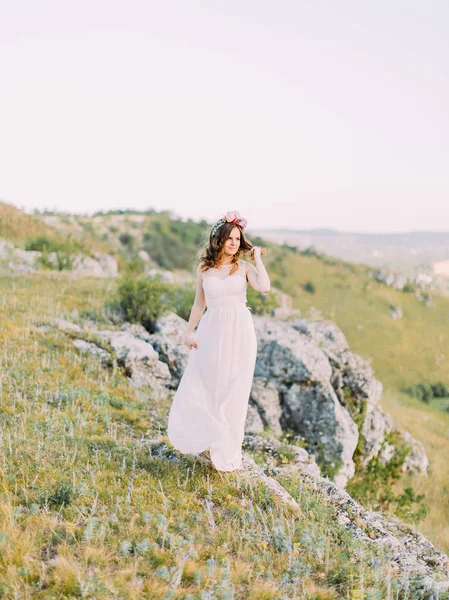 Fullängds beskåda av bruden att vidröra hennes hår och tittar åt sidan på backgroud över bergen. — Stockfoto