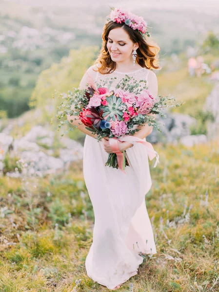 Vyn upp leende bruden håller den enorma brudbukett i bergen. — Stockfoto