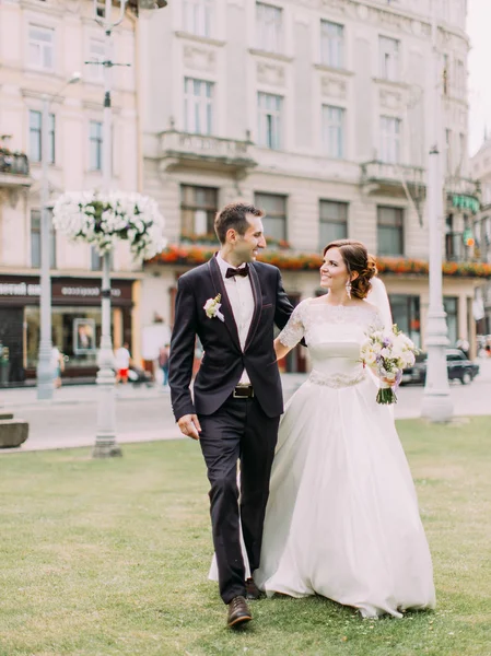 Preciosa foto de la pareja recién casada abrazada sonriente caminando por la calle . —  Fotos de Stock